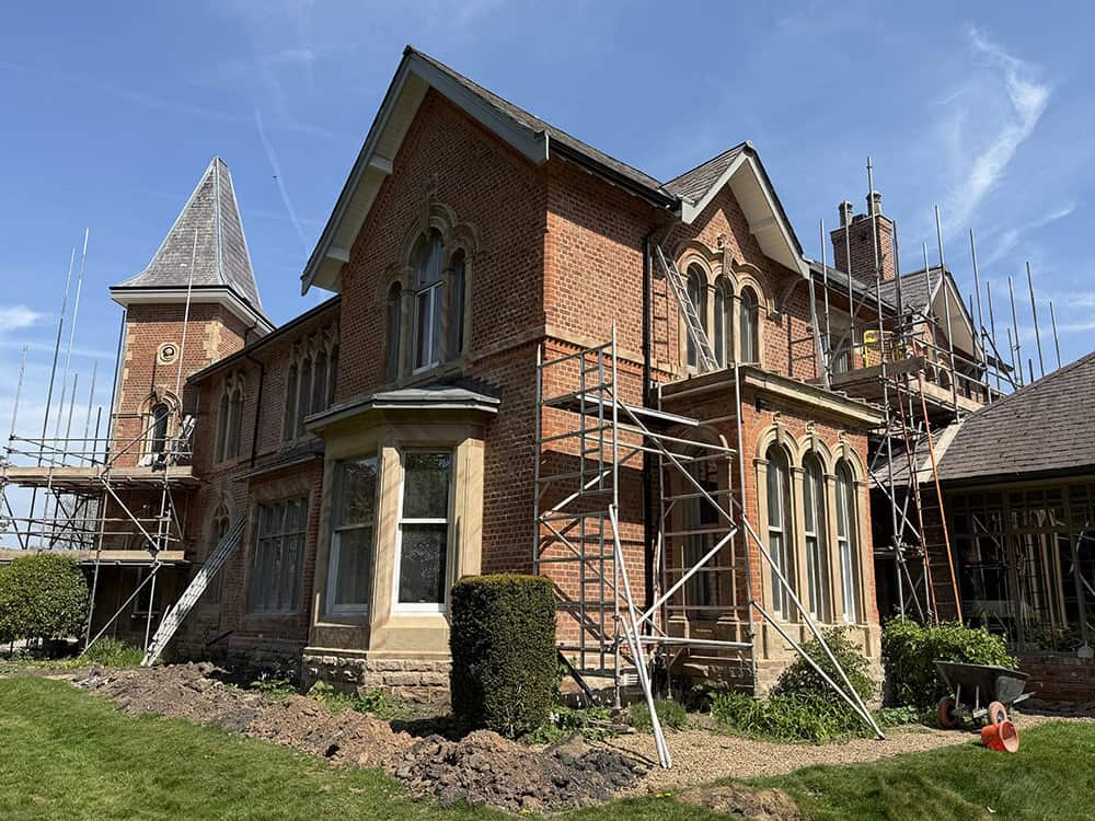 Historic brick building undergoing restoration with scaffolding in Cheshire.