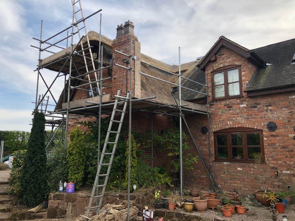 Scaffolding around a brick chimney for repointing work at a residential property.